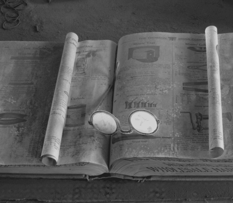 Old book with rolled up page and glasses